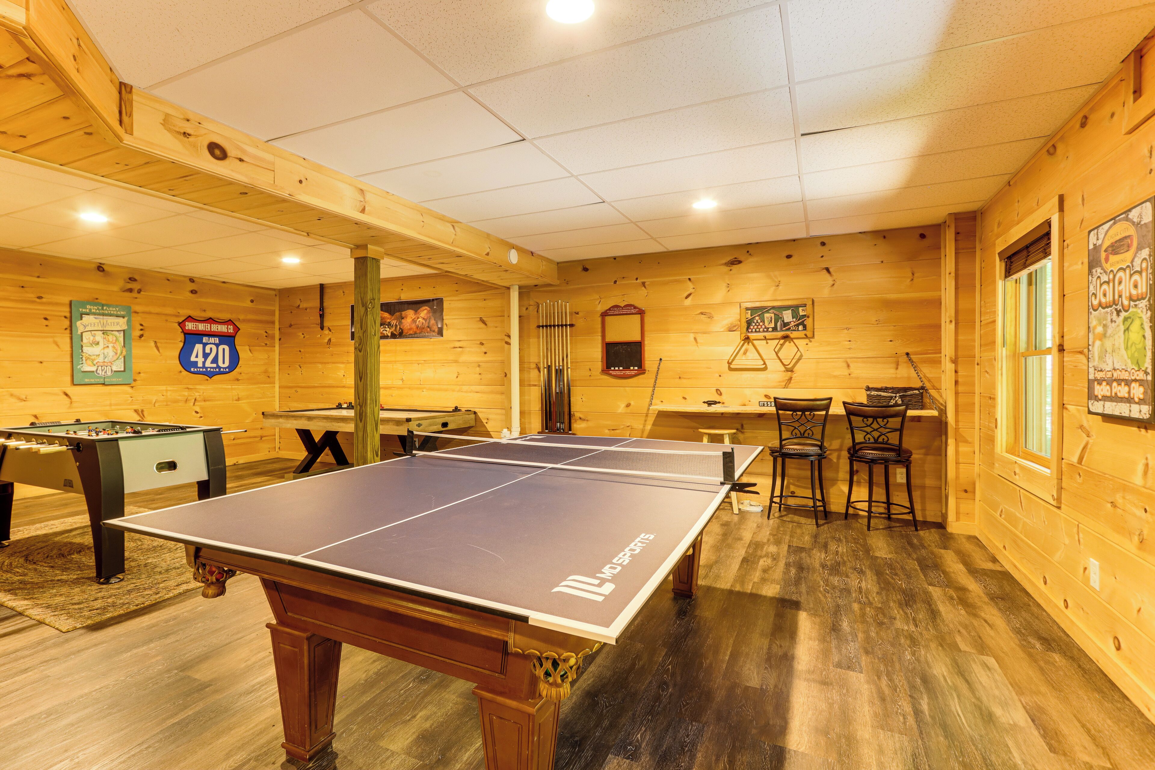 Une pièce en bois équipée d’une table de ping-pong, d’un baby-foot et d’une table de billard.