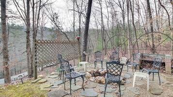 An outdoor seating area with stone tiles, metal chairs, and a fire pit.