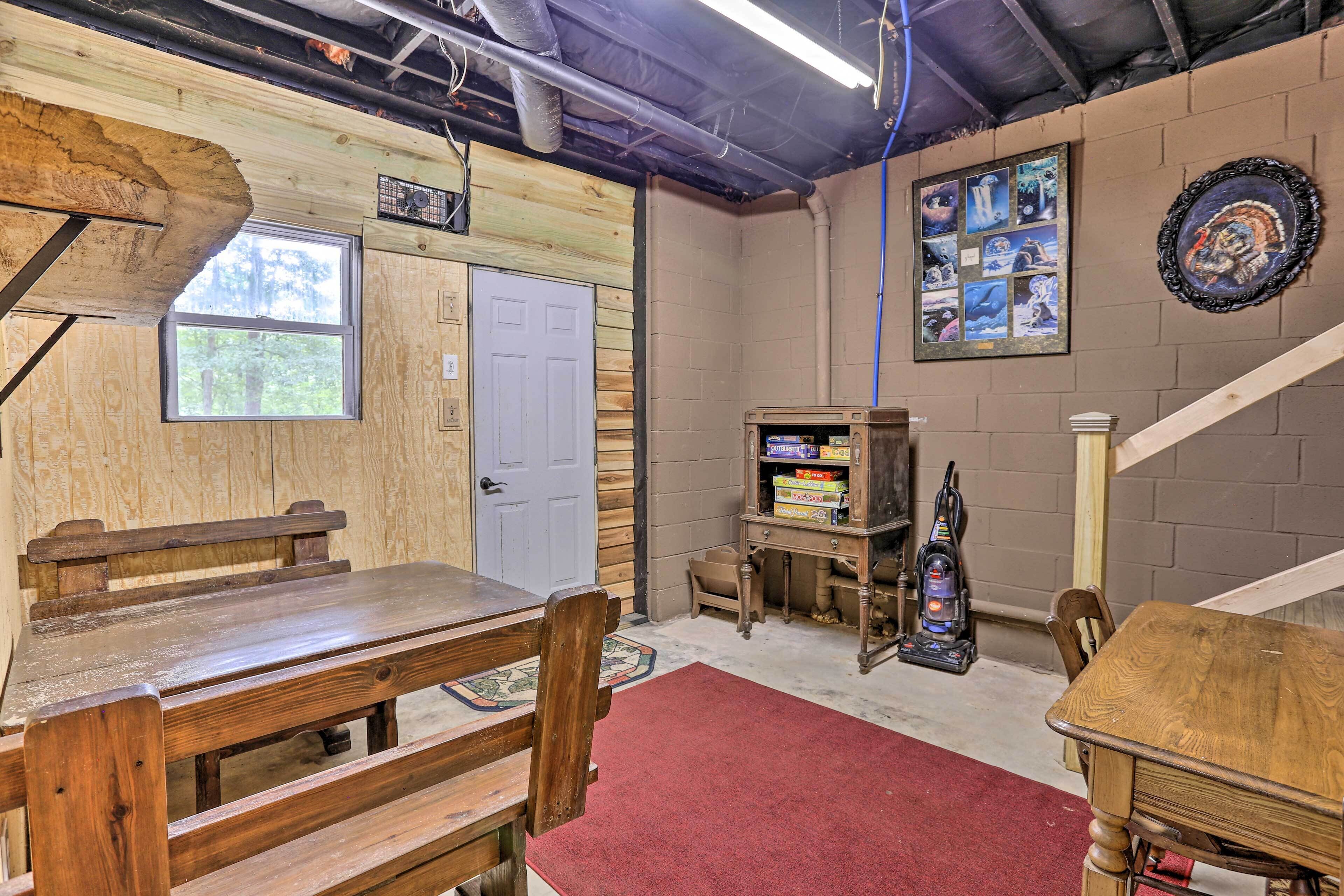 A room with a wooden bench, a table, a red carpet, a door, and a shelf with books and a vacuum cleaner.