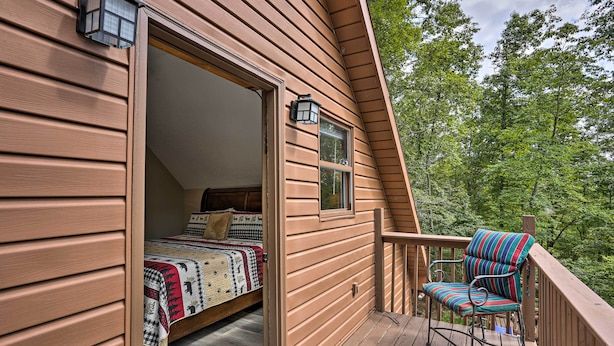 Une chambre avec un lit, une fenêtre et une chaise sur une terrasse en bois.
