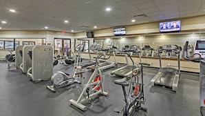 Une salle de sport équipée de divers appareils d’exercice, notamment des tapis de course et des appareils de musculation elliptique.