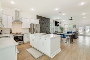 A modern kitchen with white cabinetry, a central island, and a built-in oven.