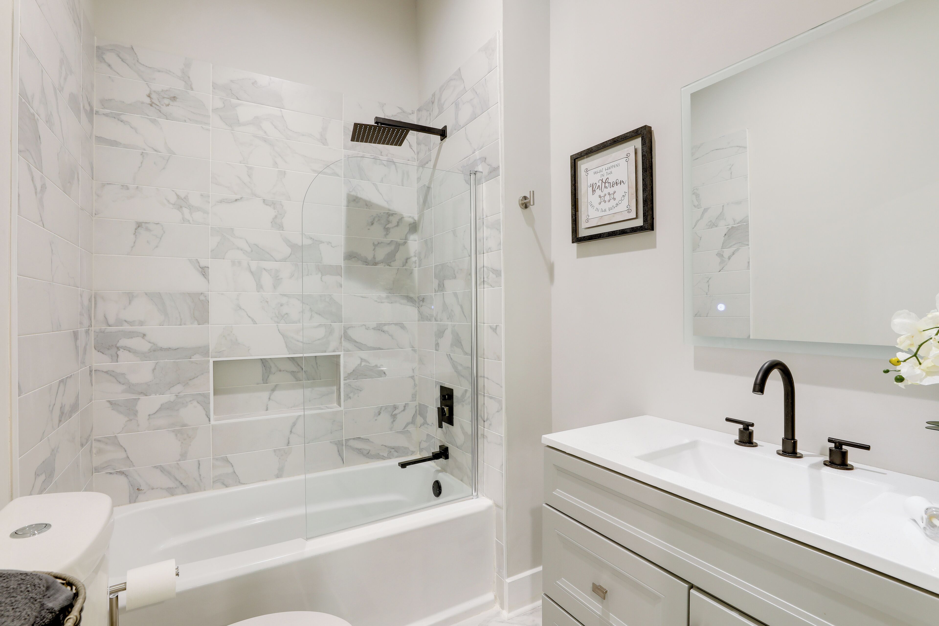 A bathroom with a bathtub, a toilet, a sink, and a shower with a glass door.