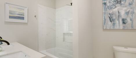 Une salle de bain moderne avec une douche en marbre, des toilettes et un lavabo.