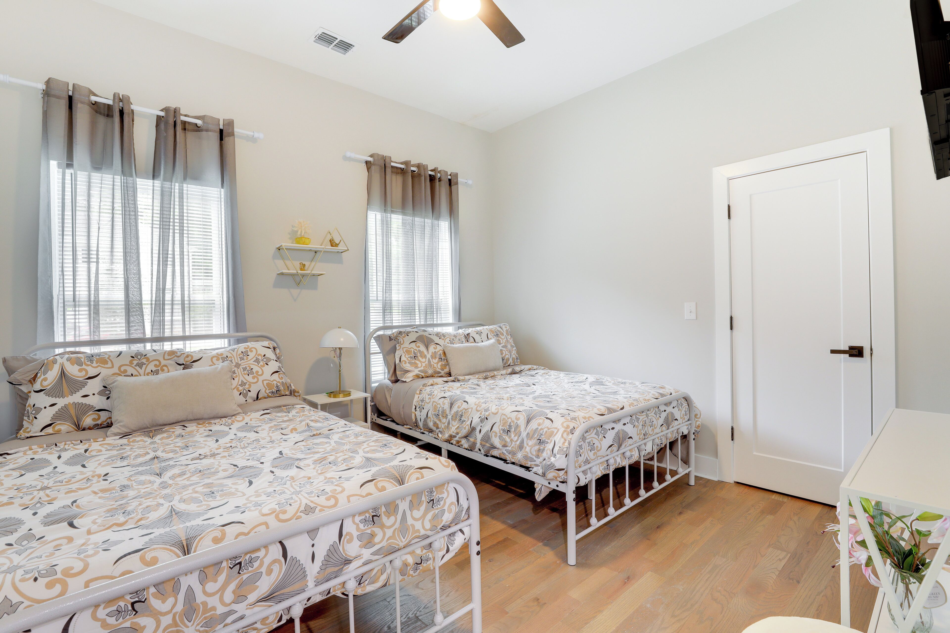 A bedroom with two beds, a white door, and a small table with a plant.