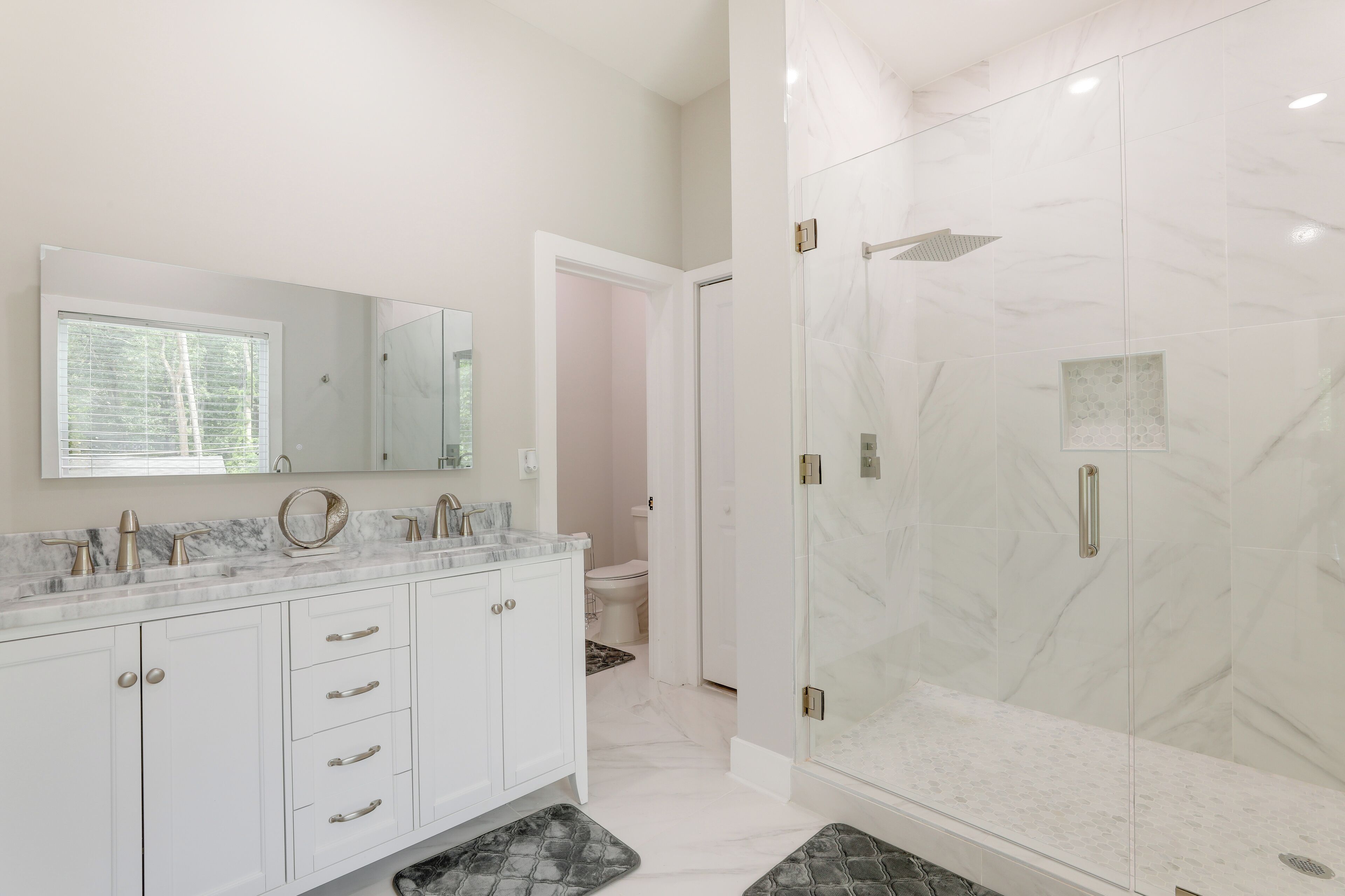 A modern bathroom with a marble vanity, a glass shower enclosure, and a walk-in shower.