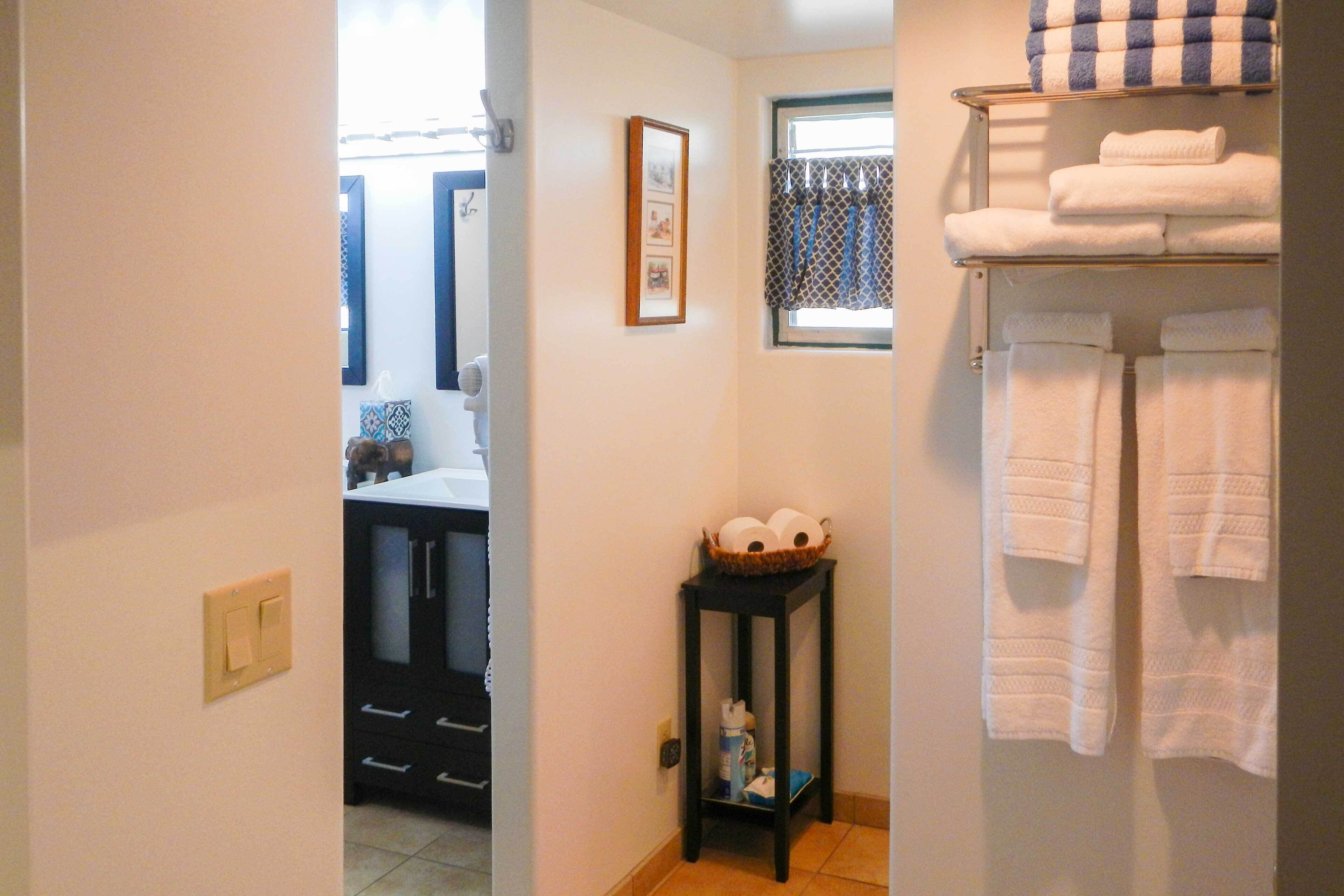 A bathroom with a towel rack, a framed picture, and a small table with a basket.