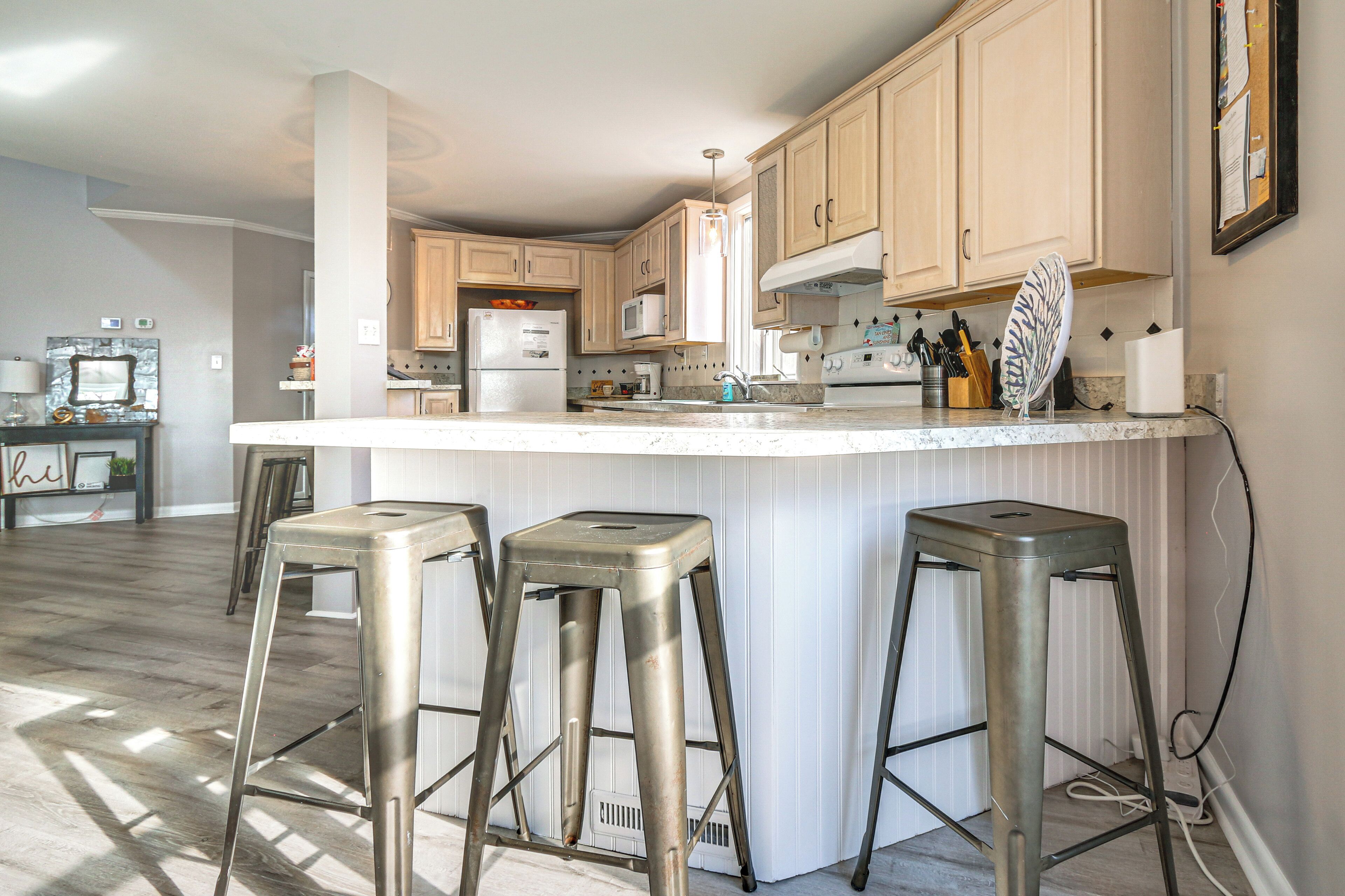 A kitchen with a central island, bar stools, and modern appliances.
