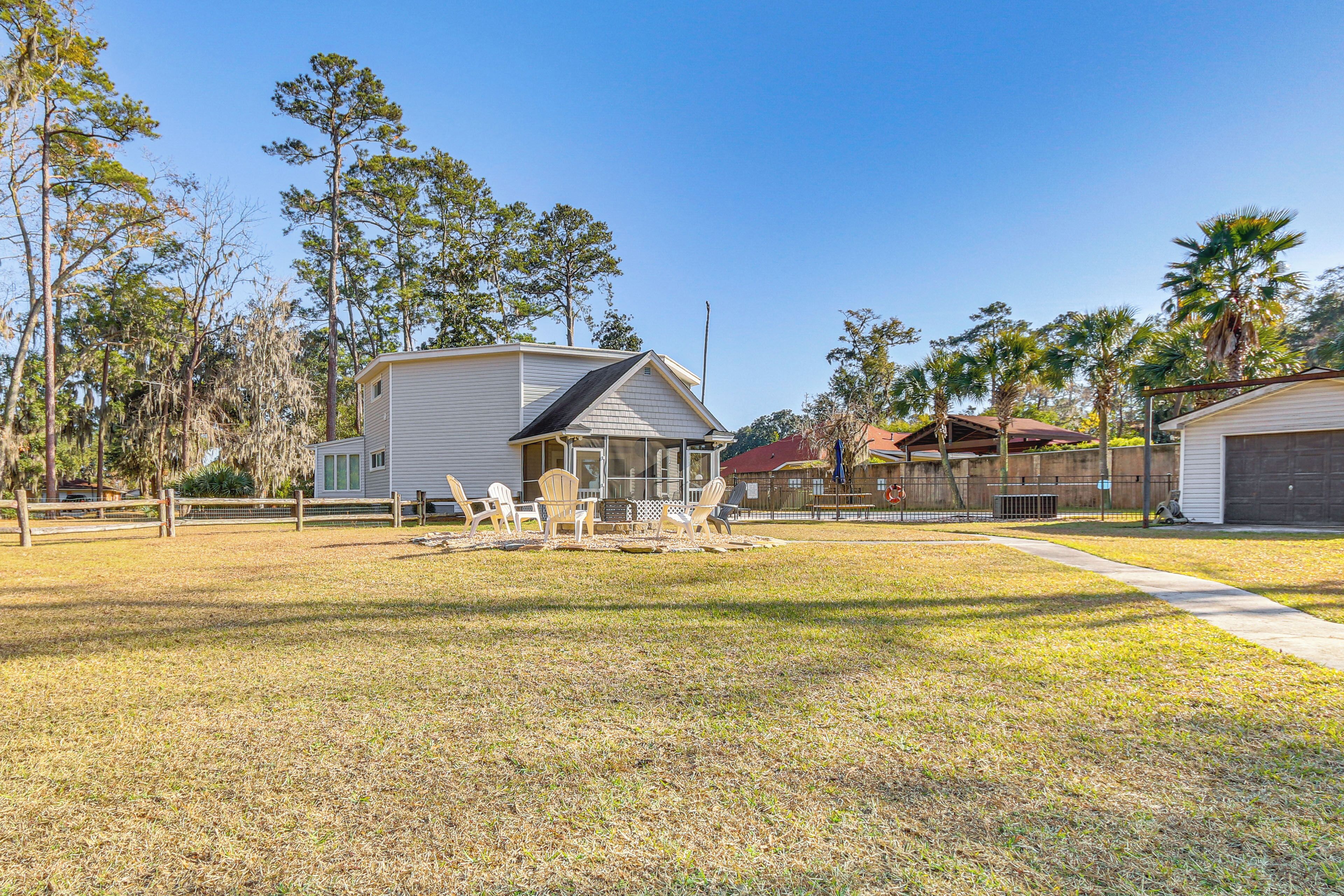 A residential area with a large house, a fenced yard, and several smaller buildings.