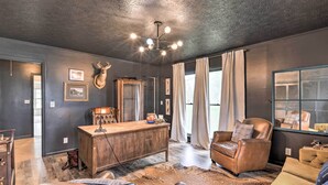 A room with a wooden desk, leather chairs, a deer head mounted on the wall, and a large mirror. - Charming Retreat on 80-acre Willow Rock Ranch! (Woodbury)