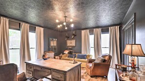 A room with a wooden desk, leather chairs, a sofa, and a chandelier. - Charming Retreat on 80-acre Willow Rock Ranch! (Woodbury)