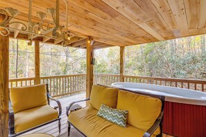 A wooden deck with a sofa and chairs, a hot tub, and a view of trees. - 'little Fox Den Ellijay Cabin Rental w/ Hot Tub! (Ellijay)