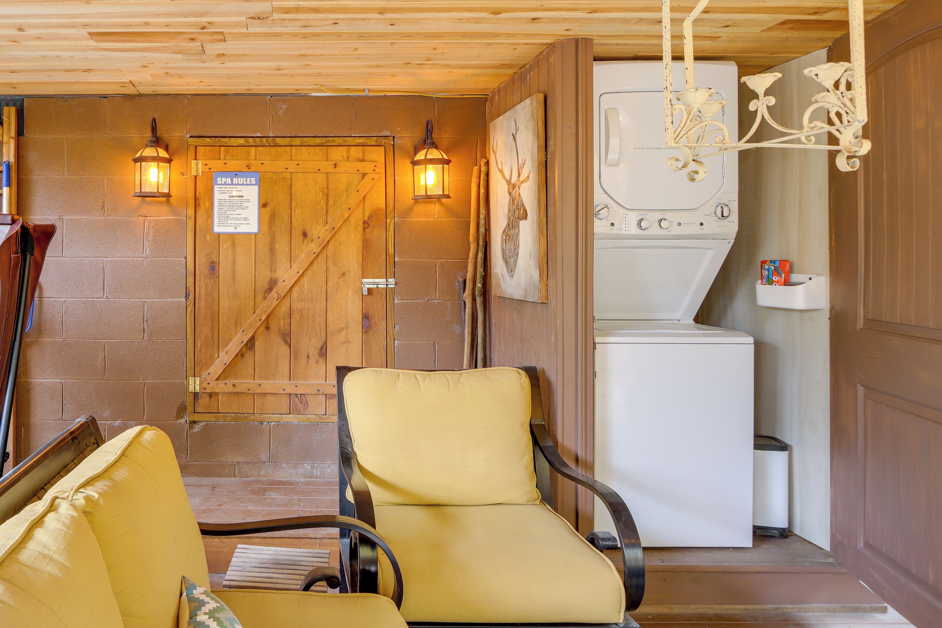 A room with a wooden door, a yellow chair, a white washing machine, and a sign with spa rules.