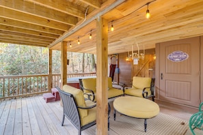 A wooden deck with yellow chairs and a table, a laundry room sign, and a door with a sign. - 'little Fox Den Ellijay Cabin Rental w/ Hot Tub! (Ellijay)