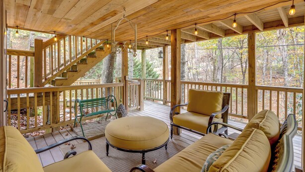 A wooden deck with a staircase, outdoor seating, and a view of trees. - 'little Fox Den Ellijay Cabin Rental w/ Hot Tub! (Ellijay)