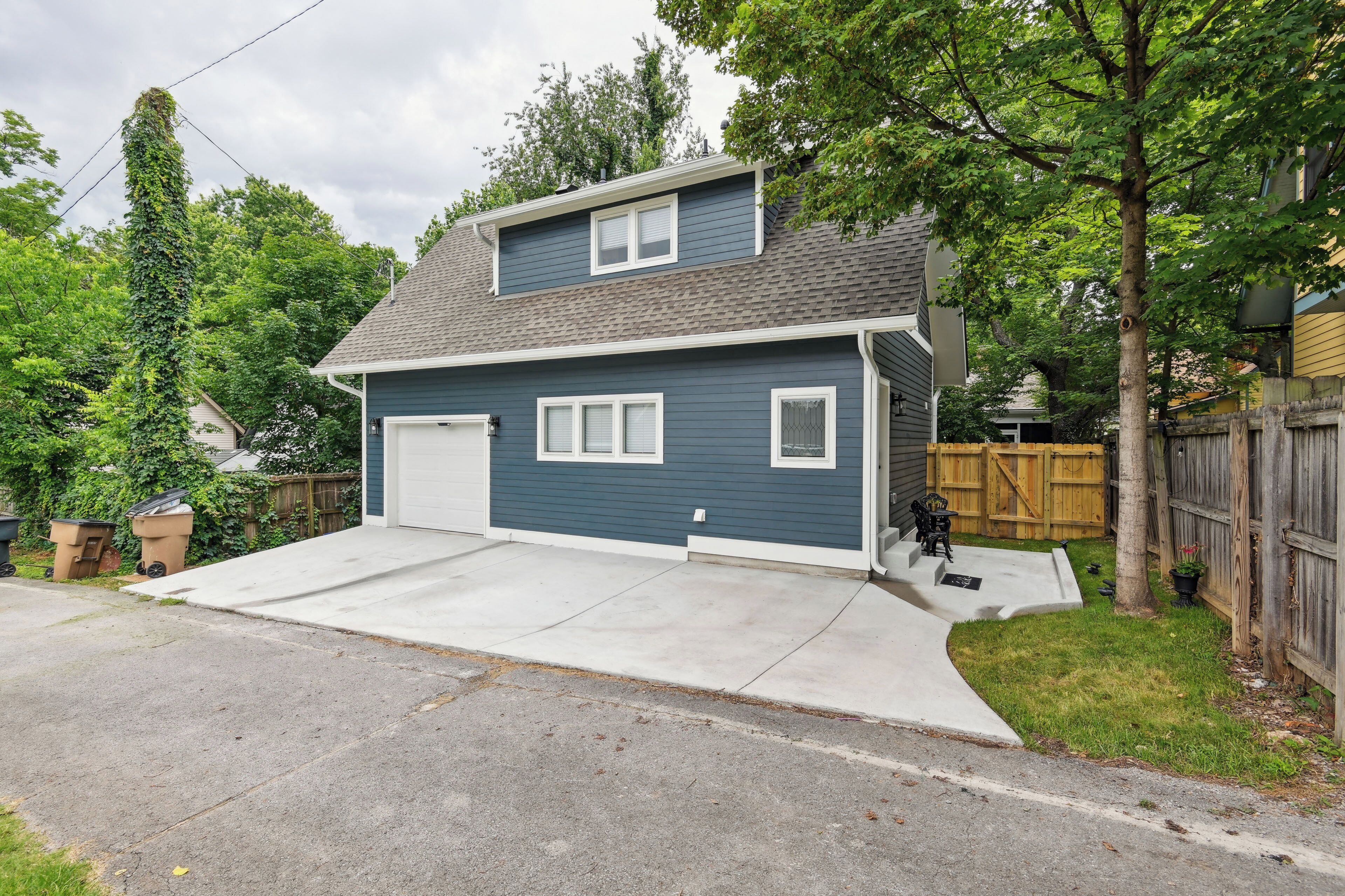 A two-story house with a garage, a front yard, and a wooden fence.