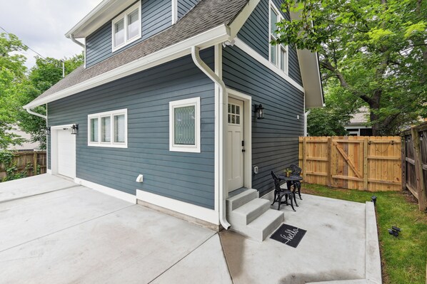 A two-story house with a front porch, a garage, and a wooden fence.