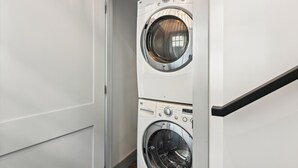A modern laundry room with two stacked front-loading washing machines. - Nashville Vacation Rental Near Bridgestone Arena! (Nashville)