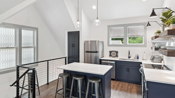 A modern kitchen with a central island, bar stools, a stainless steel refrigerator, and a window with blinds. - Nashville Vacation Rental Near Bridgestone Arena! (Nashville)