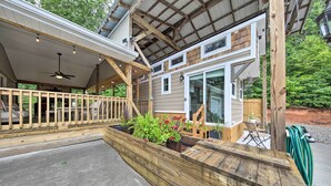 A covered outdoor area with a wooden deck, a ceiling fan, and potted plants. - Blairsville Tiny Home w/ Covered Furnished Deck! (Blairsville)