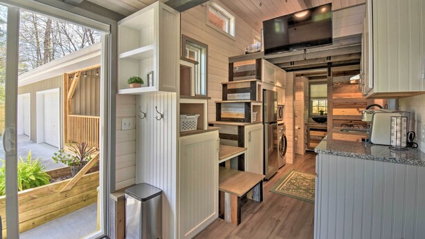 A compact kitchen with built-in appliances, wooden flooring, and a view of the outdoors. - Blairsville Tiny Home w/ Covered Furnished Deck! (Blairsville)