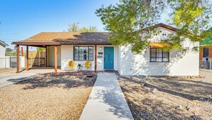 A single-story house with a front porch, a blue door, and a small garden area with a gravel path leading to the entrance. - Spacious Yard + Patio: Central Tucson Retreat! (Tucson)
