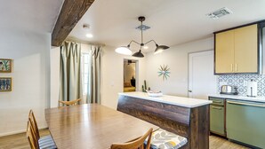 A dining area with a wooden table and chairs, a kitchen with green cabinets, and a decorative star on the wall. - Spacious Yard + Patio: Central Tucson Retreat! (Tucson)