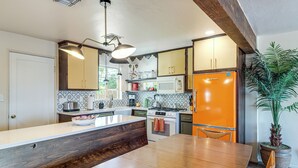 A kitchen with a wooden island, a microwave, a stove, and a refrigerator. - Spacious Yard + Patio: Central Tucson Retreat! (Tucson)