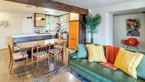 A modern kitchen with wooden cabinets, a dining table, and a sofa with colorful cushions. - Spacious Yard + Patio: Central Tucson Retreat! (Tucson)