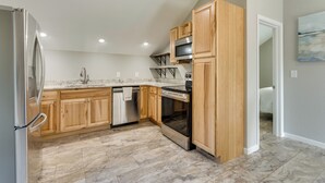 A modern kitchen with wooden cabinets, stainless steel appliances, and a tiled floor. - Young Harris Vacation Rental w/ Mountain Views! (Young Harris)