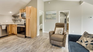 A modern kitchen with wooden cabinets and stainless steel appliances, a leather recliner, and a blue sofa with patterned cushions. - Young Harris Vacation Rental w/ Mountain Views! (Young Harris)