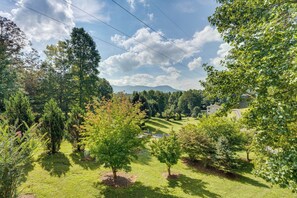 A lush green landscape with trees and a distant view of a house.