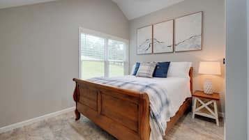 Une chambre à coucher avec un lit en bois, une table de chevet, une lampe et une fenêtre avec des stores.
