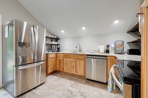 A modern kitchen with stainless steel appliances, wooden cabinets, and a tiled floor. - Young Harris Vacation Rental w/ Mountain Views! (Young Harris)