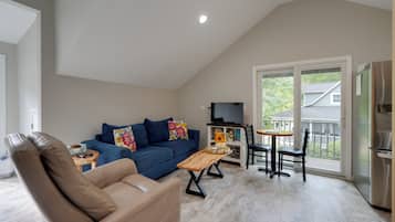 Un salon spacieux avec un plafond haut, un canapé, une table basse et un téléviseur.