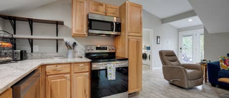 A modern kitchen with wooden cabinets, a built-in microwave, and a stainless steel oven.
