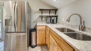 A kitchen with a stainless steel refrigerator, wooden cabinets, a granite countertop, a double sink, and a coffee machine. - Young Harris Vacation Rental w/ Mountain Views! (Young Harris)