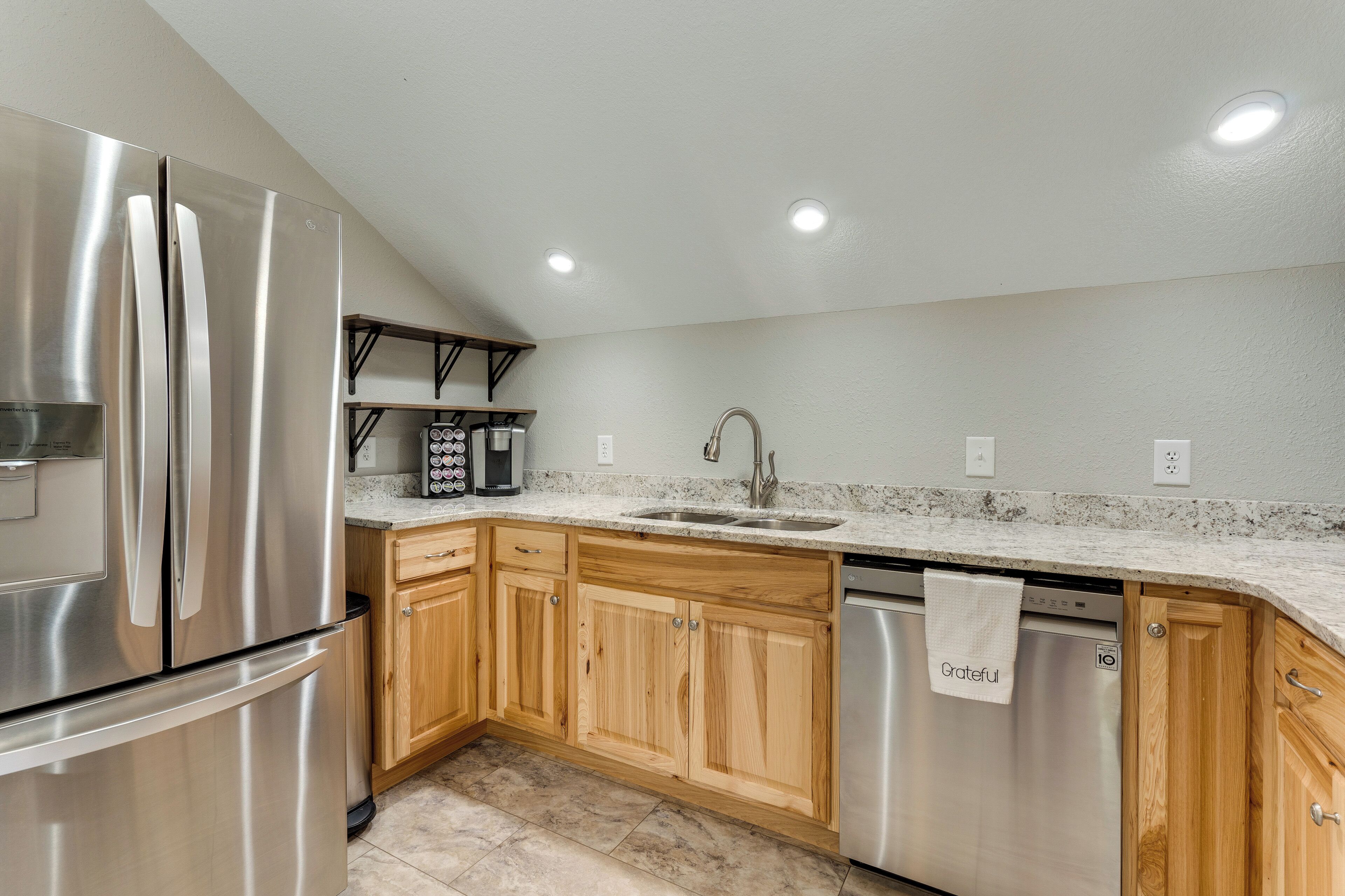 A kitchen with stainless steel appliances, wooden cabinets, a granite countertop, and a built-in dishwasher.