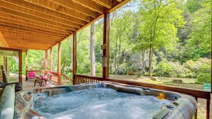 A hot tub in a wooden deck with a view of a forested area. - Private Cartecay River Home w/ Hot Tub & Game Room (Ellijay)