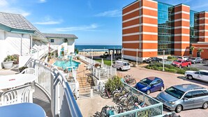 A hotel with a pool, a beach view, and a parking area with cars and bicycles. - Chic Virginia Beach Retreat - Pool, Steps to Beach (Virginia Beach)