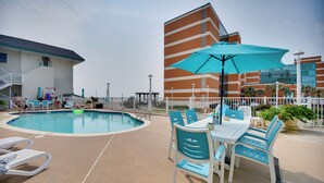 A pool area with lounge chairs and a table with a blue umbrella. - Chic Virginia Beach Retreat - Pool, Steps to Beach (Virginia Beach)