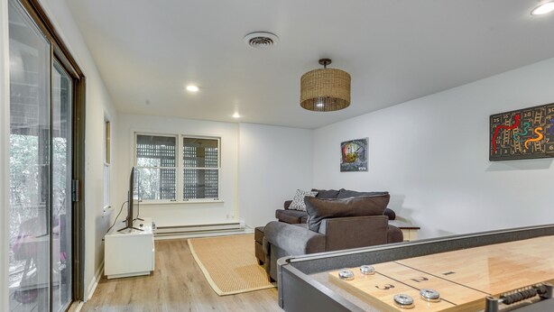 Une pièce avec une table de billard, un canapé, une fenêtre et un luminaire au plafond.