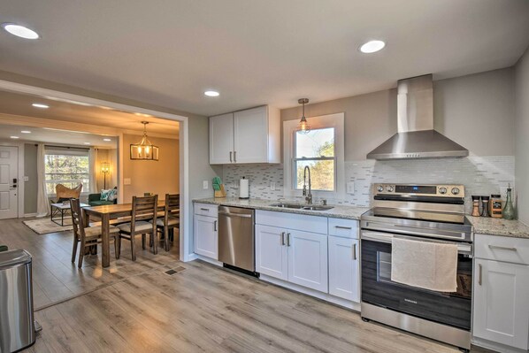 A modern kitchen with white cabinets, a stainless steel range, and a dishwasher.