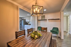 A dining area with a wooden table, chairs, and a hanging light fixture. - Private Yard + Fire Pit: Commerce Home! (Commerce)