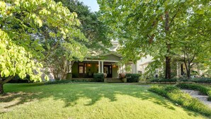 A house with a front porch, surrounded by a well-maintained lawn and trees. - New Memphis Midtown Apt: 2 mi to Overton Square! (Memphis)