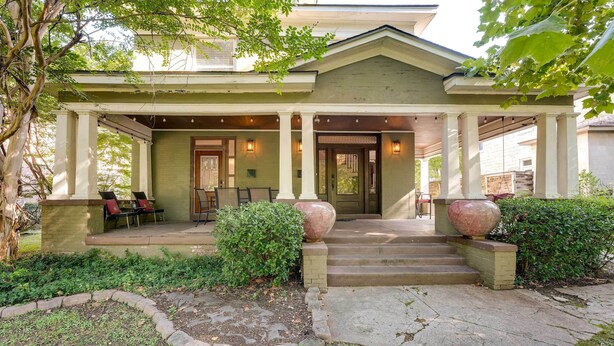 A two-story house with a covered porch, steps leading to the front door, and a small garden area with a bench and potted plants. - New Memphis Midtown Apt: 2 mi to Overton Square! (Memphis)