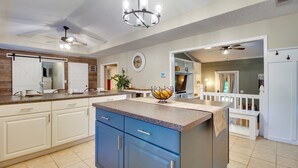 A spacious kitchen with a central island, white cabinetry, and a ceiling fan. - Southern Escape in Guyton: Private Yard & Hot Tub! (Guyton)