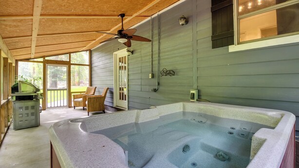 A hot tub in a covered outdoor area with a ceiling fan, wooden deck, and a view of the outdoors. - Southern Escape in Guyton: Private Yard & Hot Tub! (Guyton)