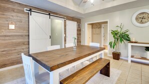 A dining area with a wooden table, white chairs, a bench, a ceiling fan, and a wall clock. - Southern Escape in Guyton: Private Yard & Hot Tub! (Guyton)