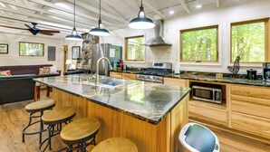 A modern kitchen with a large island, bar stools, and a built-in microwave. - Stunning Culloden Cabin With Deck & Creek View! (Roberta)